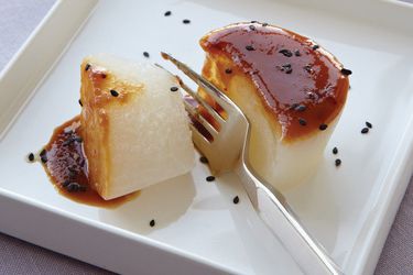 Braised daikon radish on a square plate, sprinkled with black sesame seeds.