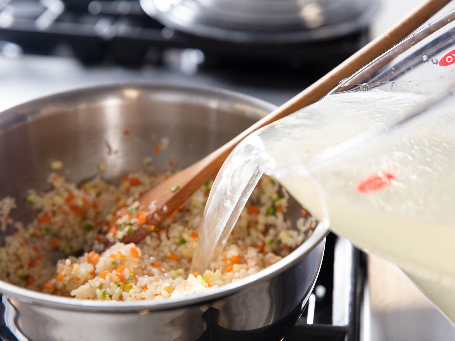 把高汤倒入一锅米饭和切碎的蔬菜gydF4y2Ba