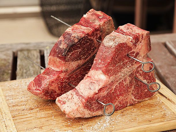 两块调味的上等腰牛排横着放，里脊肉部分朝上。它们被串在一起，中间有2英寸的空隙。