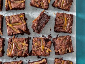 Ginger spiced brownies laid out on a slice of parchment paper.