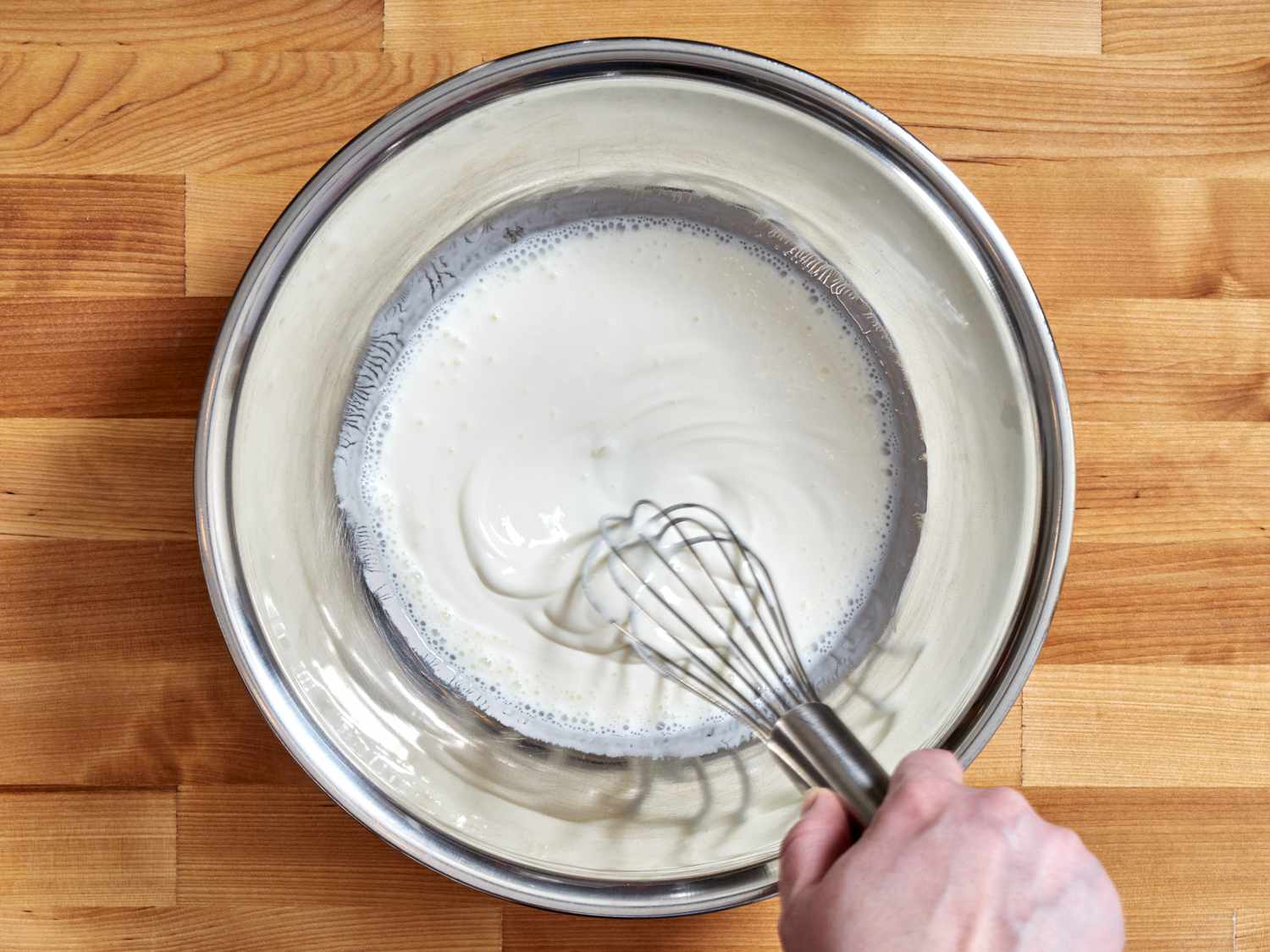 白脱牛奶and sour cream being whisked together in a bowl.