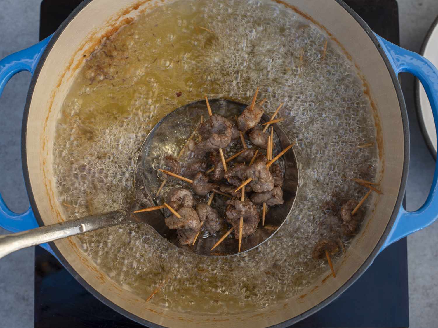 滤网将油炸的牙签羊肉从荷兰烤箱的油炸油中取出