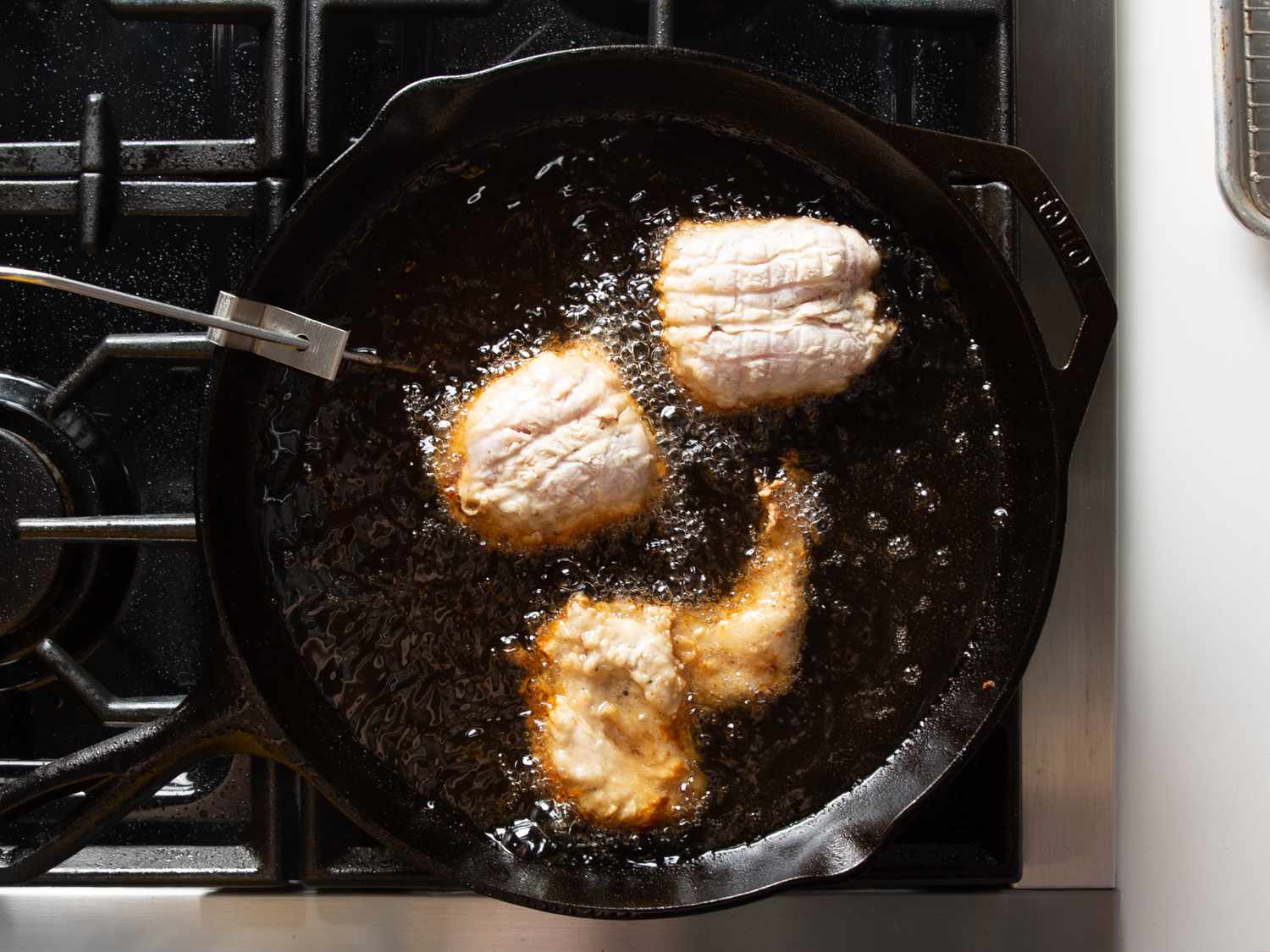 头顶上的照片，第二批卤水和疏浚鸡肉正在铸铁煎锅中煎