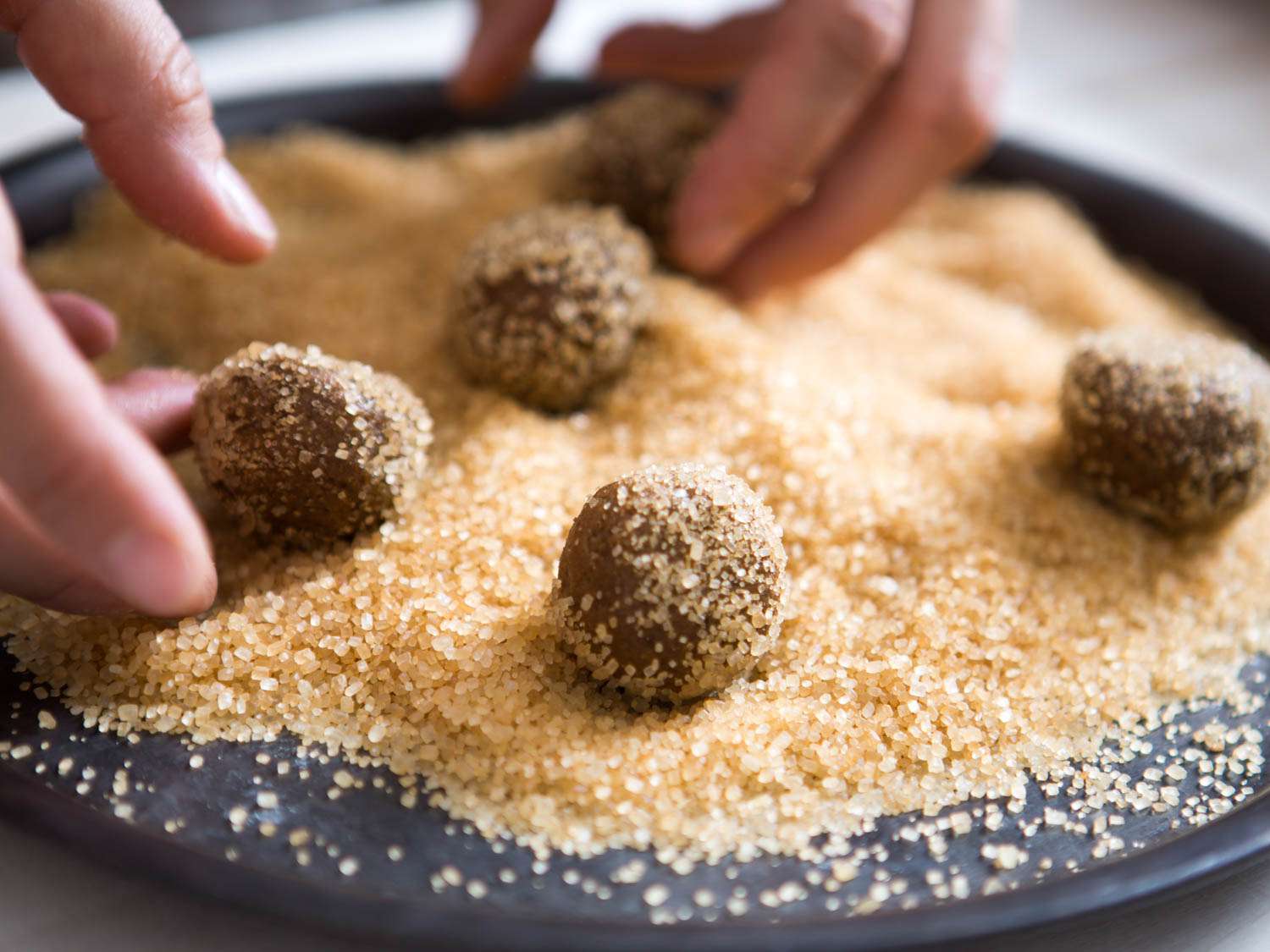 Rolling balls of gingersnap cookie dough in turbinado sugar.