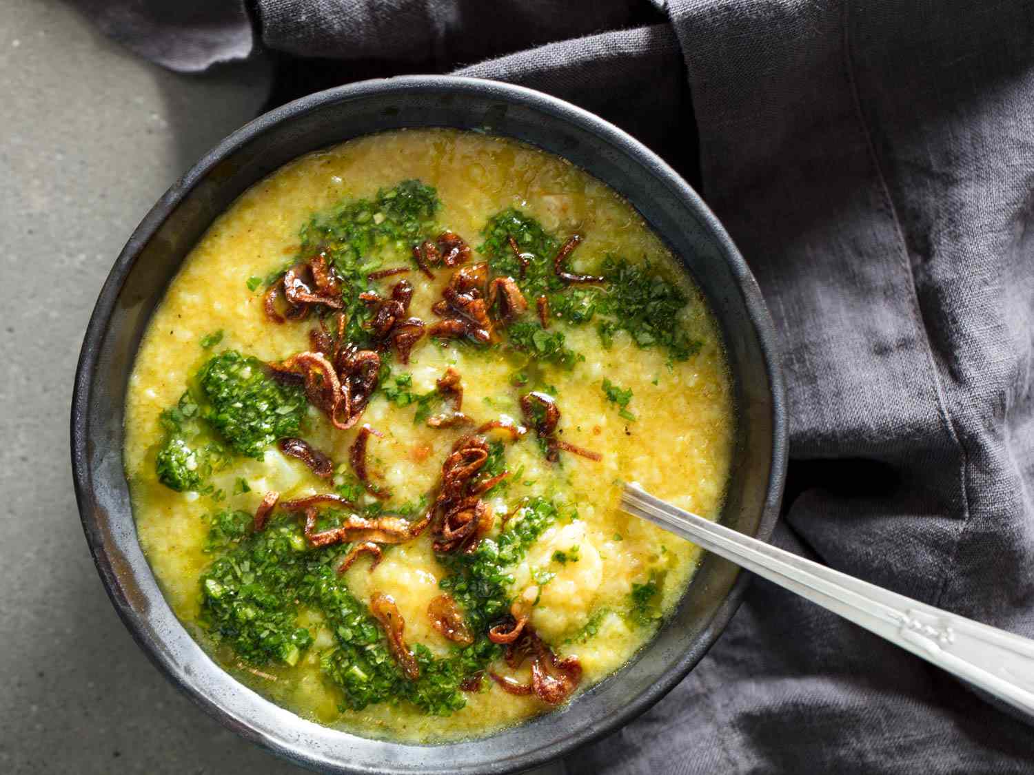 Overhead shot of a spoon dug into a bowl of Bengali rice porridge with lentils and chicken