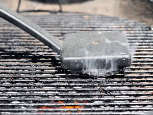 Cleaning a grill grate with a steel brush.