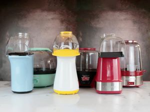 a lineup of six different popcorn makers against a dark background