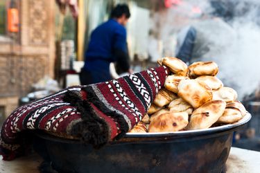 samsas, unleavened pockets of wheat dough that are filled with mutton, folded over like envelopes, and then baked in a deep outdoor pit