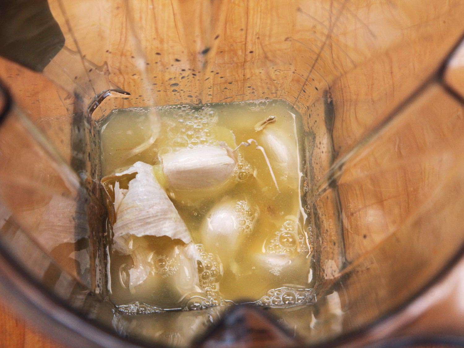 Blending whole unpeeled garlic cloves and lemon juice to make creamy hummus.