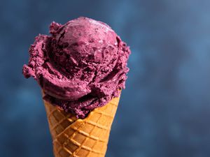 A scoop of no-churn blueberry ice cream on a waffle cone.