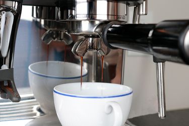 an espresso shot with thick streams is dropping into a cup