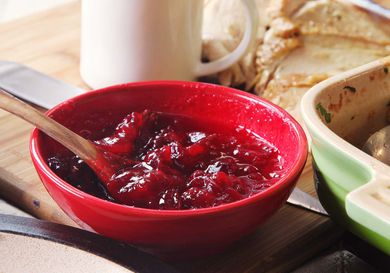 世界上最简单的红碗蔓越莓酱，旁边是砂锅菜，背景是烤火鸡和肉汁罐。