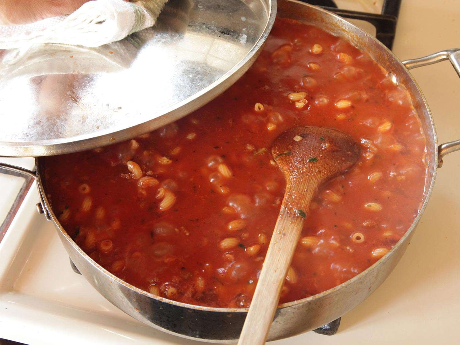锅盖裂开的煎锅镜头，木勺在搅拌锅里的东西。