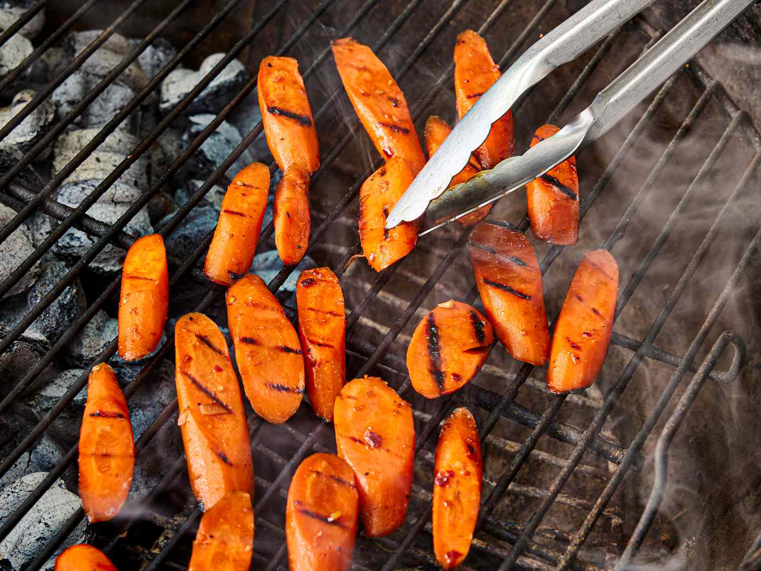 Overhead view of flipping carrots on the grill