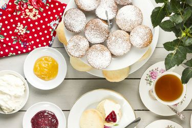 A table full of different British sweets and a cup of tea.