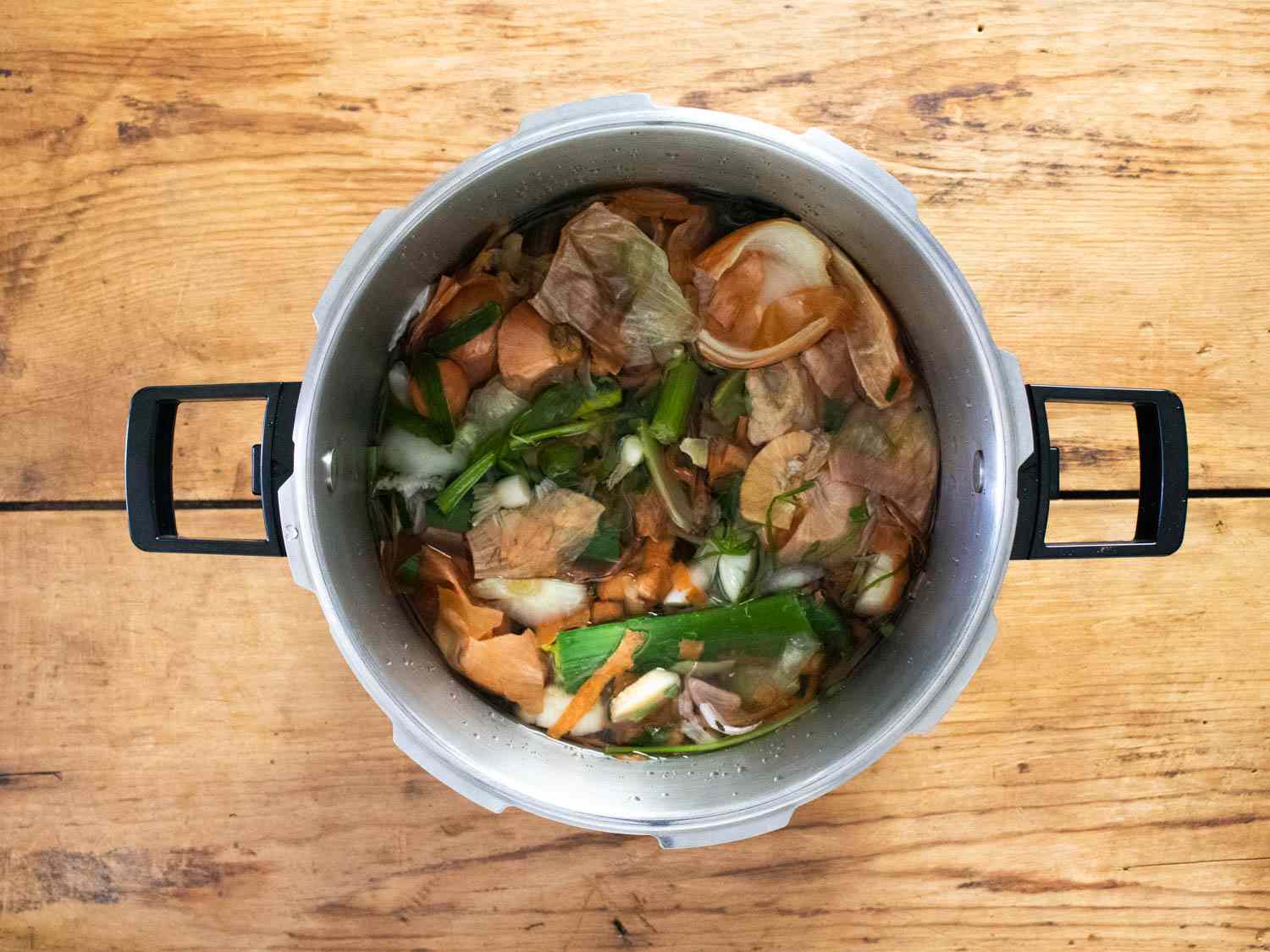 Overhead view of a pressure cooker filled with vegetable scraps.