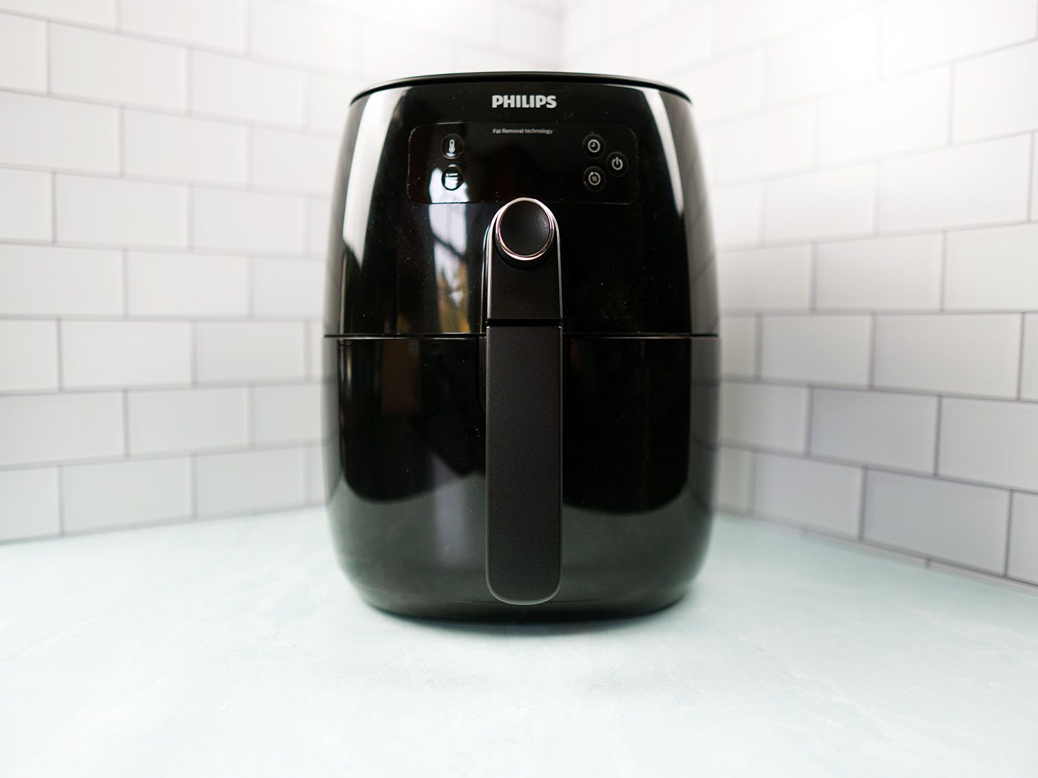 a small black air fryer sitting on a blue surface
