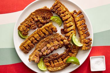 Overhead view of chicharrones on a plate with a small bowl of salt off to the side