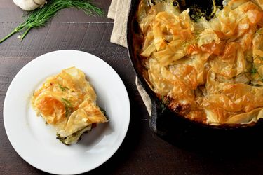 Flaky phyllo over a spinach and chicken filling, with plenty of creamy garlic-feta sauce. Pictured here, a full skillet with a plateful of the dish next to it.