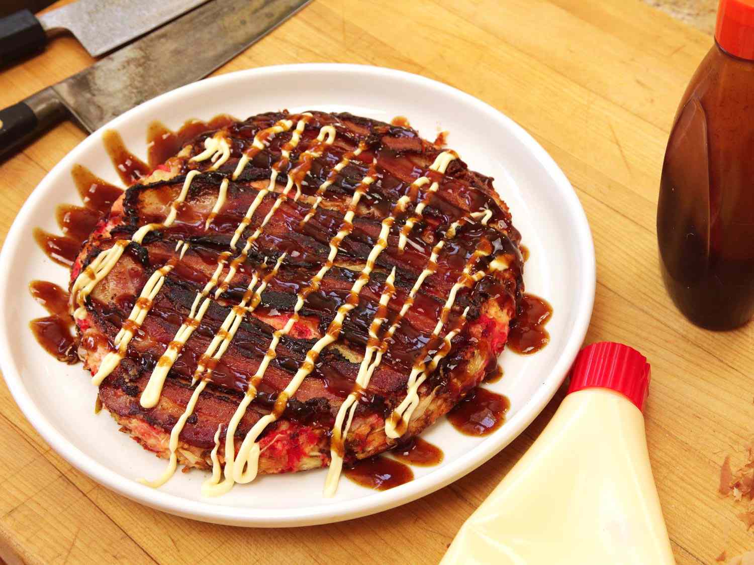 An okonomyaki, a savory Japanese pancake, covered in kewpie drizzle