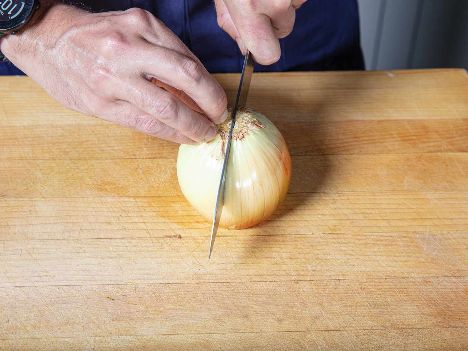 在砧板上把去皮的洋葱切成两半。