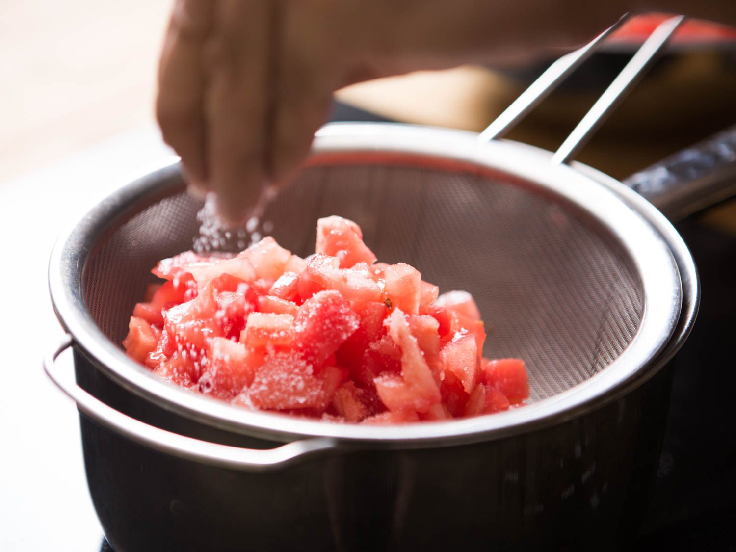 在筛子里用盐腌蕃茄丁。