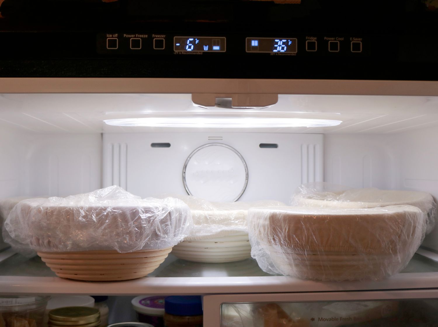 five bread proofing baskets on a shelf in a refrigerator