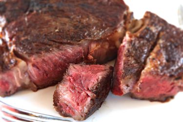 A steak that's been reverse-seared, cut into pieces on a plate.