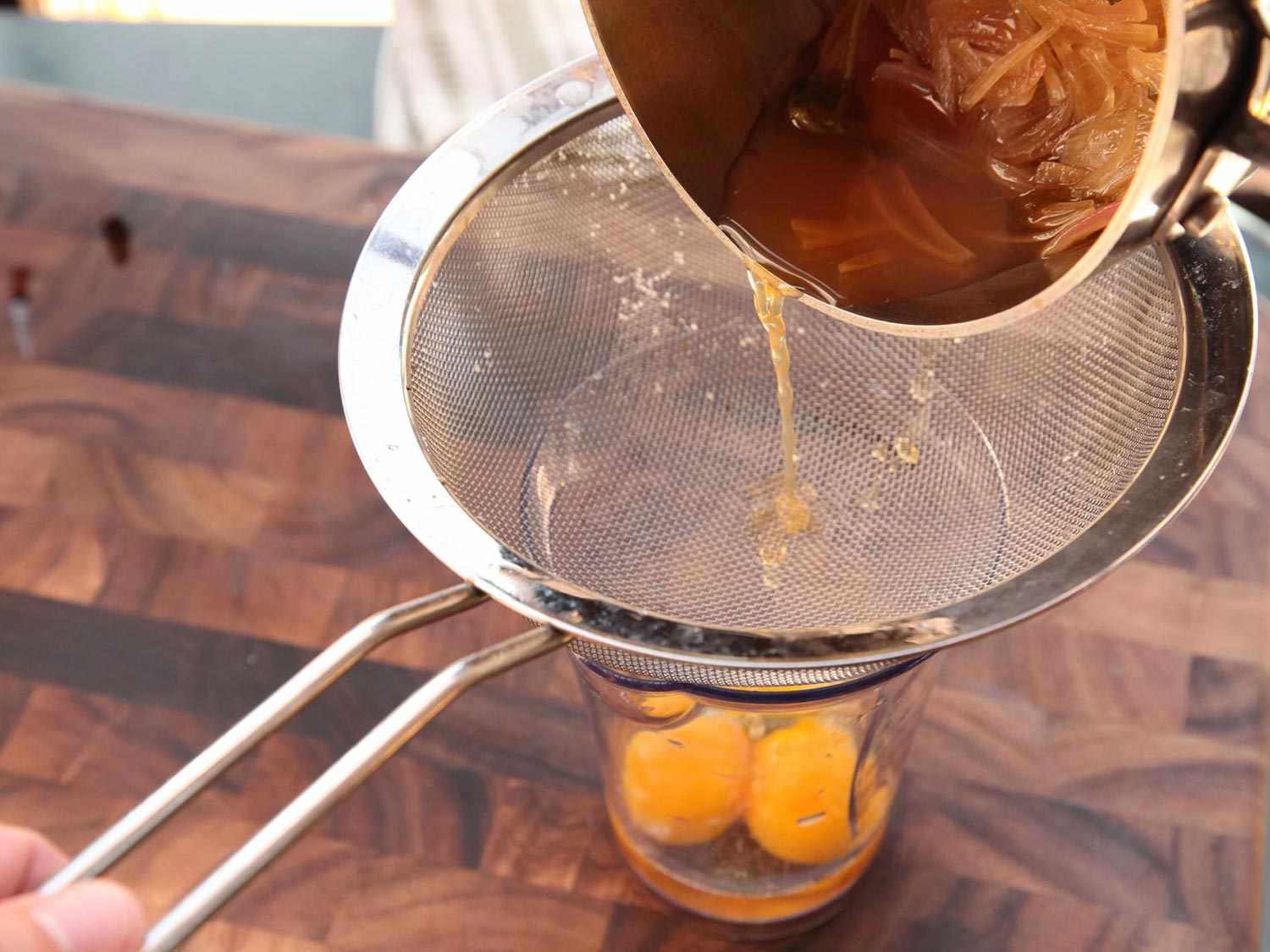 用滤网将浸泡过的醋倒入与蛋黄混合的坛子中，制成蛋黄酱