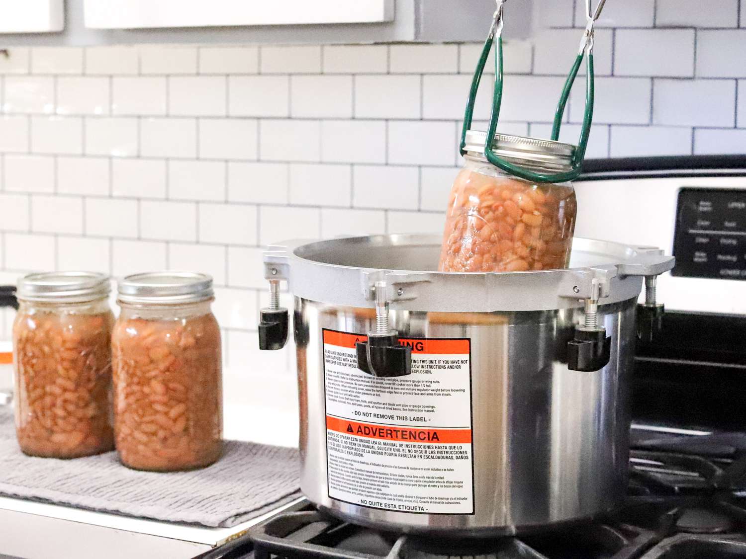 a jar of beans being lowered into an All-American brand pressure canner