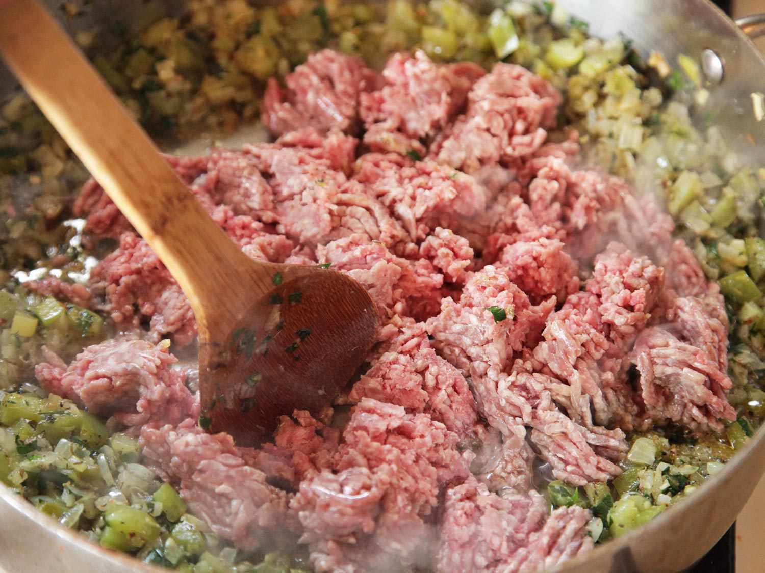 木勺把牛肉碎成小块的特写。