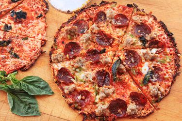 Two Extra-Crispy Bar-Style Tortilla Supreme Pizzas, cut into wedges on a wooden cutting board.