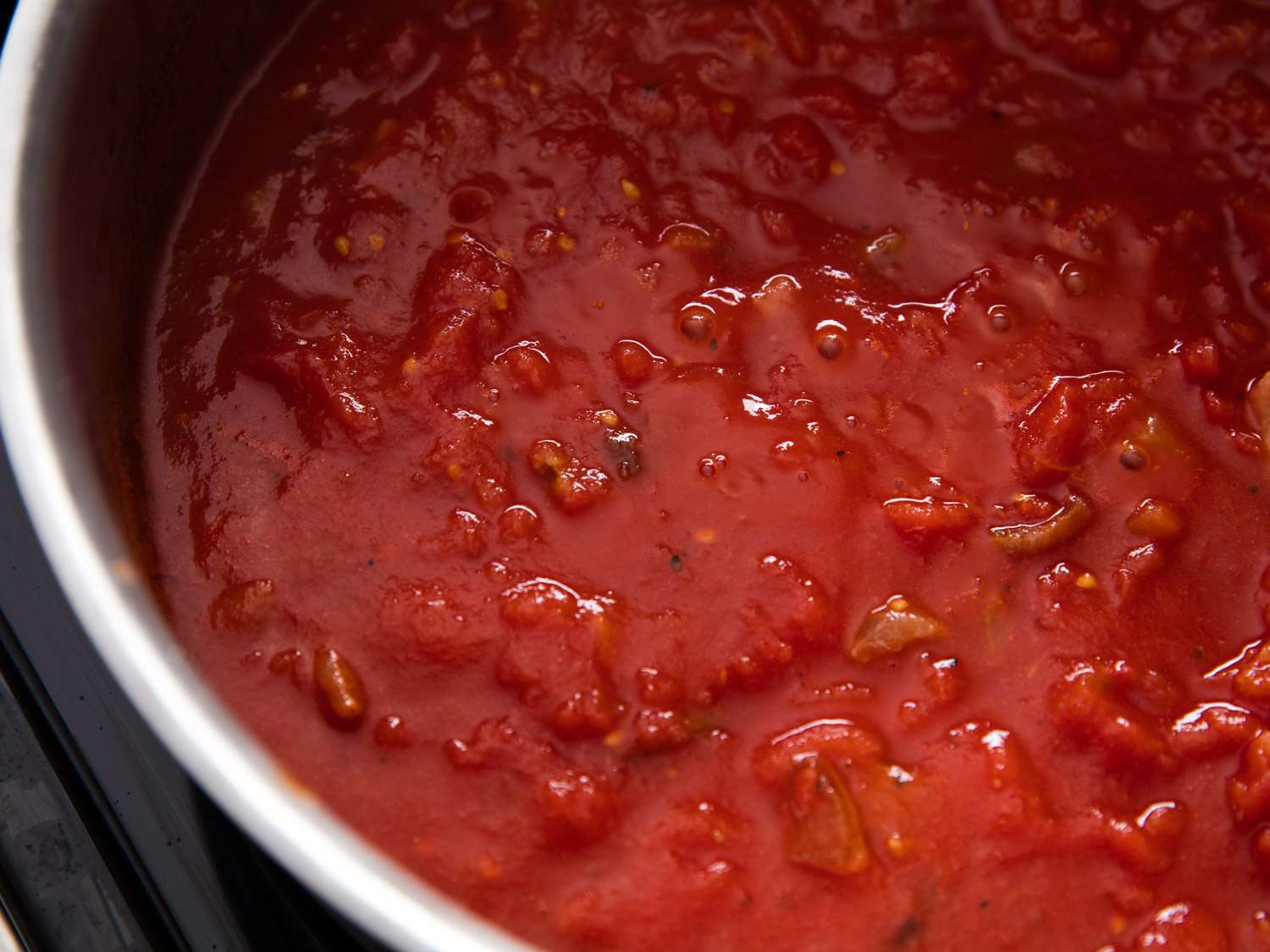 Close-up overhead shot of a pot of tomato sauce simmering.