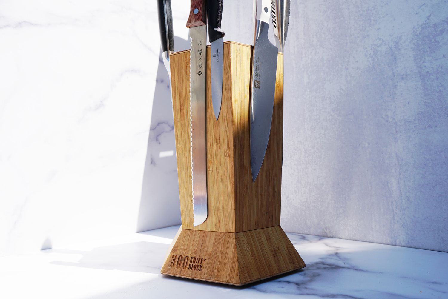 a 360 knife block on a marble surface with several knives on it