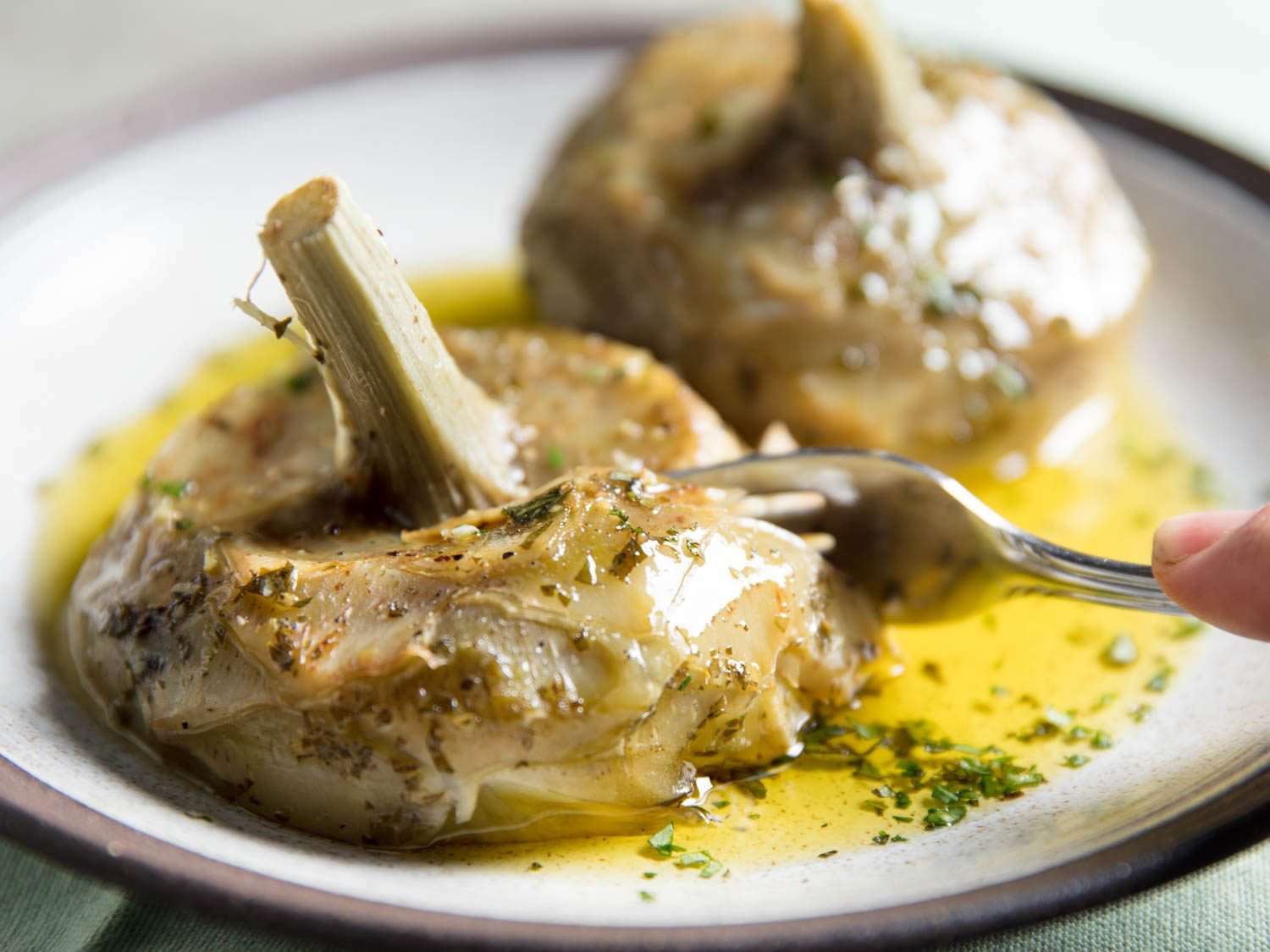 Closeup of Roman braised artichoke hearts being cut with the side of a fork.