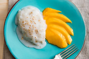 Overhead of coconut sticky rice on a plate with slices of mango