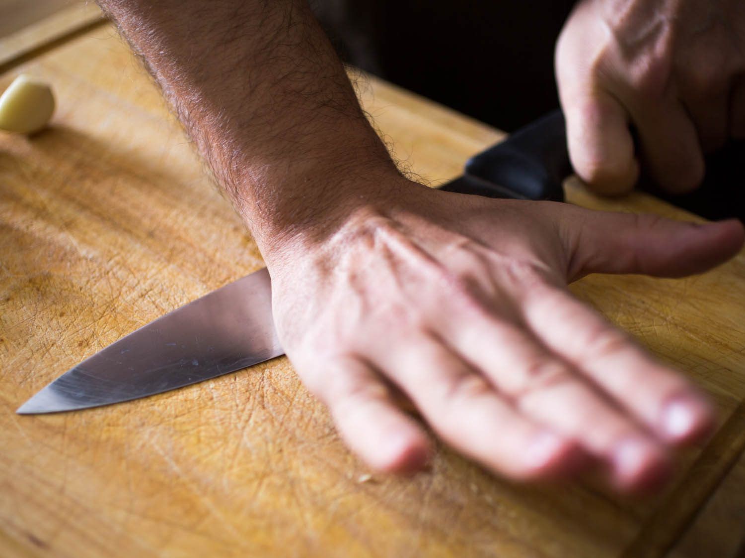 Crushing garlic with the side of a knife.