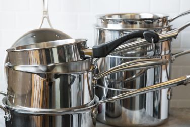 two stacks of stainless steel saucepans on a kitchen countertop