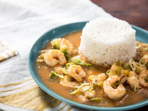 A bowl of shrimp etouffee, with a mound of white rice in the bowl.