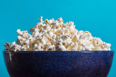 A large blue bowl piled high with popped popcorn.