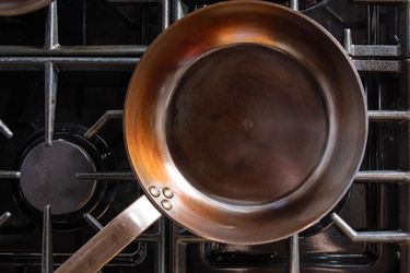 Overhead view of a freshly seasoned carbon steel pan on a gas cooktop.