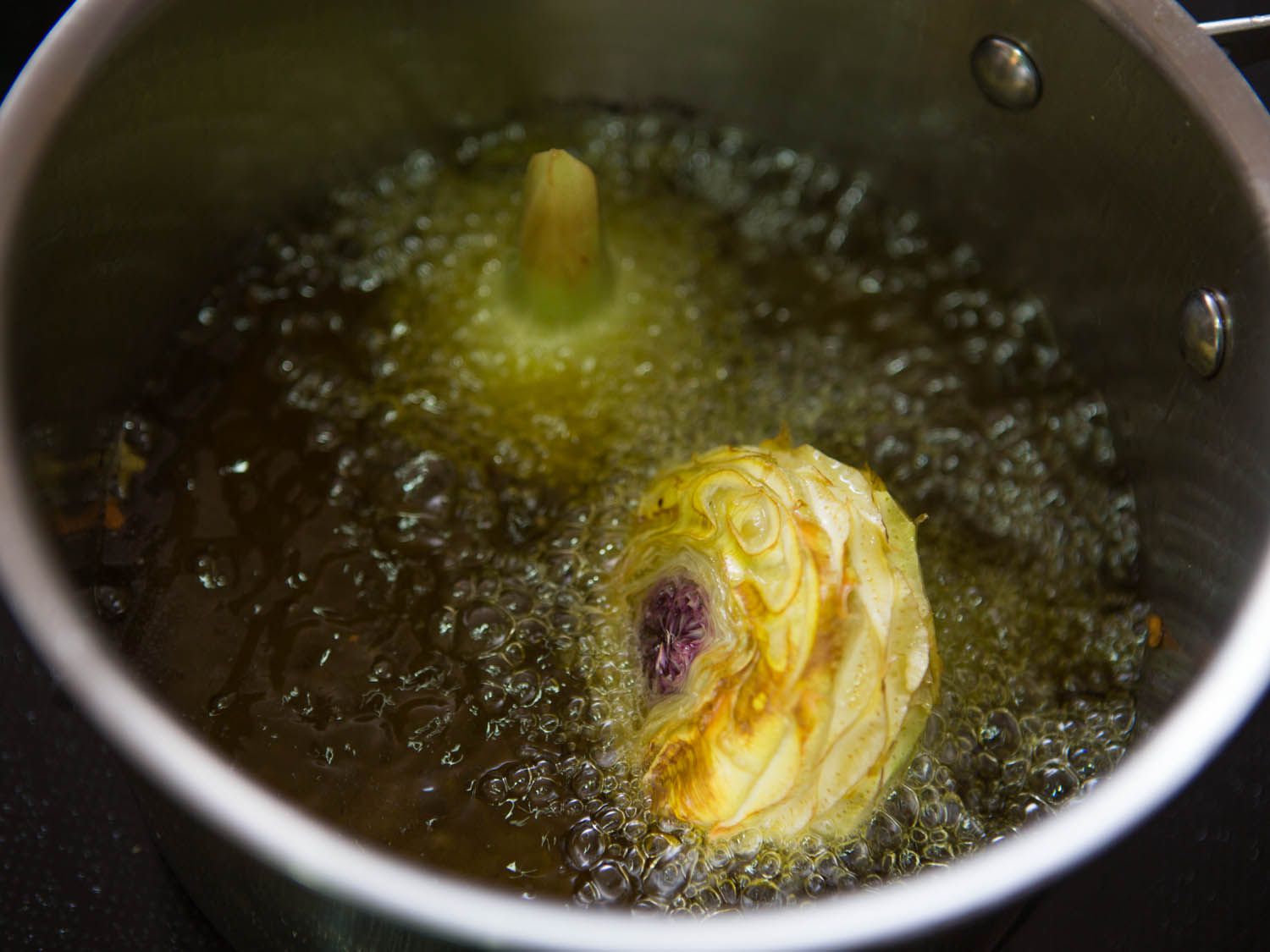 Deep-frying large trimmed artichoke hearts.