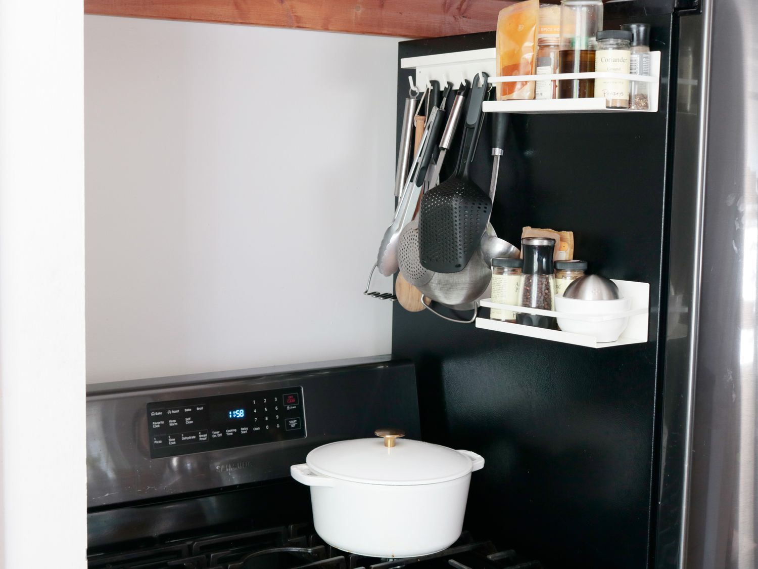 a magnetic rack holding utensils on the side of a fridge over a stovetop