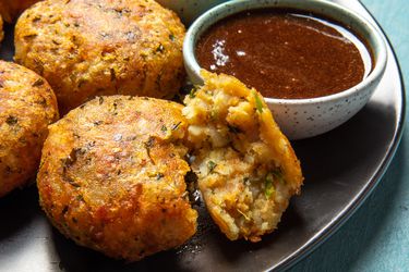 Aloo tikki on a plate with a dipper of tamarind chutney alongside