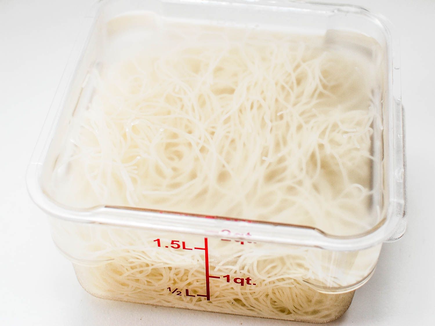 Rice vermicelli noodles sitting in a clear container with boiling water.