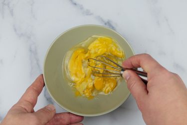 a miniature whisks beats three eggs in a bowl