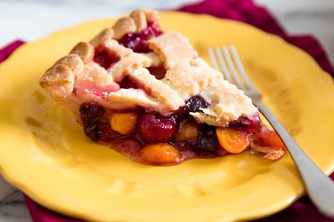 A slice of berry pie with a flaky gluten-free lattice crust.