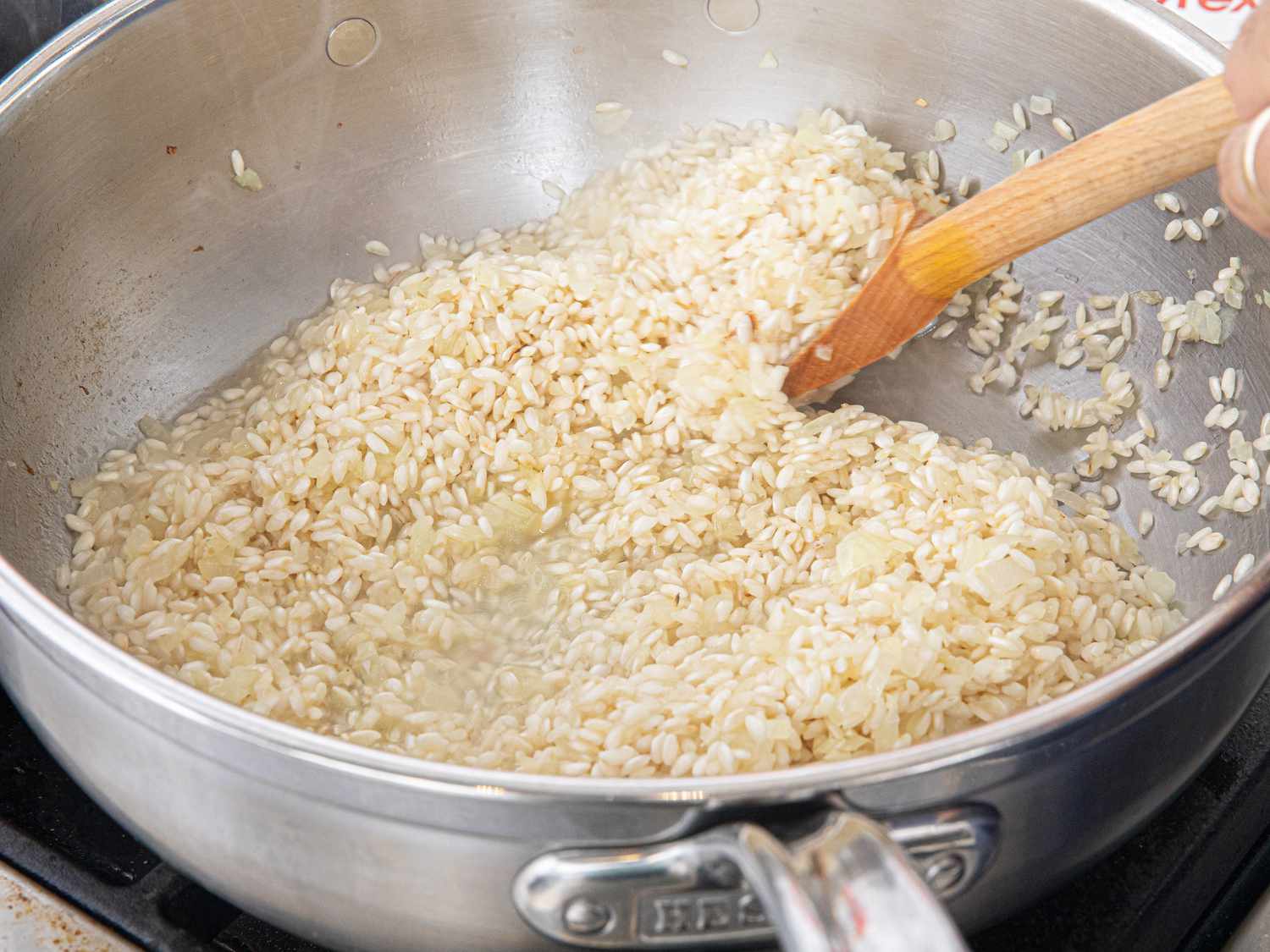 Overhead view of stirring risotto with stock