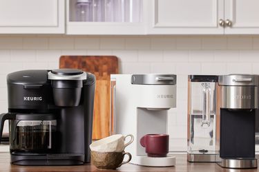 three keurigs on a stainless steel tabletops