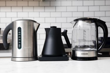 three electric kettles on a marble kitchen countertop